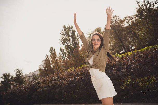 Photo of funky inspired cute woman raise hands enjoy sunny day wear brown shirt mini skirt park street outside - Photo, Image