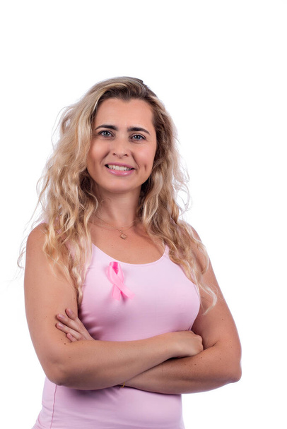 Caucásico chica con rosa camiseta celebración de cáncer de mama cinta sobre un fondo blanco. - Foto, Imagen