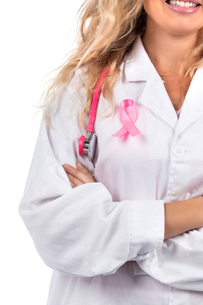 Mujer doctora caucásica con estetoscopio rosa con cinta rosa de cáncer de mama sobre fondo blanco. - Foto, Imagen