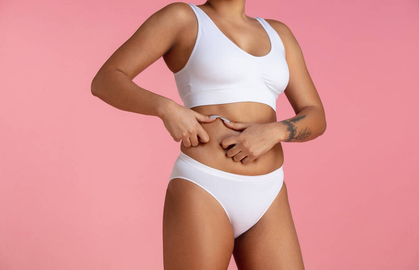 Beautiful body of young african-american woman isolated on pink studio background - 写真・画像