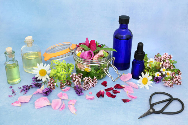 Φυσική αρωματοθεραπεία αιθέριο έλαιο προετοιμασία με καλοκαιρινά βότανα & λουλούδια για έγχυση σε έλαια. Νεκρή ζωή με μπουκάλια και ψαλίδια σε στίγματα μπλε φόντο. έννοια υγειονομικής περίθαλψης για naturopathic βοτανοθεραπευτικής. - Φωτογραφία, εικόνα