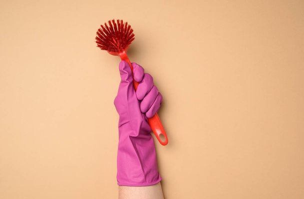 female hand in purple rubber gloves holds a plastic cleaning brush on a beige background, copy spce - Photo, Image