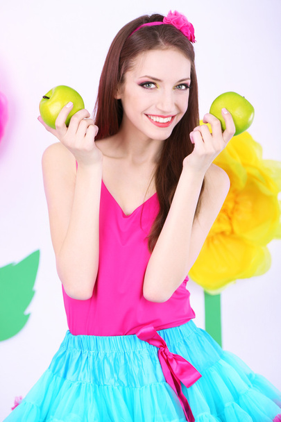 Beautiful young woman in petty skirt with apples on decorative background - Zdjęcie, obraz
