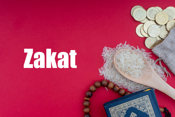 ZAKAT Worte mit dem Heiligen Koran, Münzen, Rosenkranz und Reis. Zakat-Konzept. Zakat ist eine Form von Almosen als religiöse Verpflichtung  - Foto, Bild