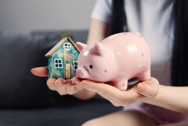 girl holding piggy bank and house model - Photo, Image