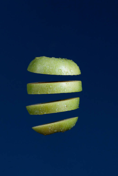 pezzi galleggianti di mela verde su sfondo blu, creativo ancora immagine dal vivo - Foto, immagini