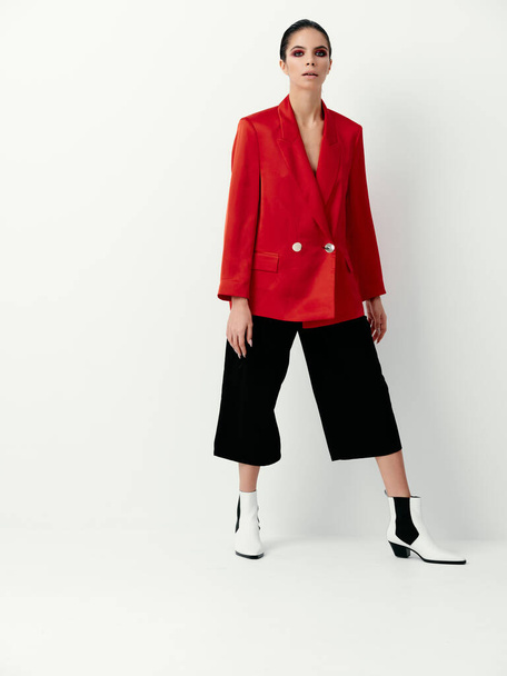 стильная брюнетка в красной куртке и модные сапоги на светлом фоне - Фото, изображение