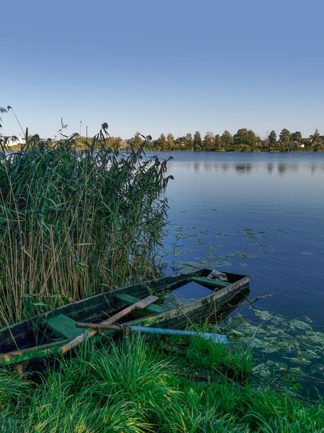 Krajina se starou shnilou dřevěnou lodí a v létě jezero s rákosím - Fotografie, Obrázek