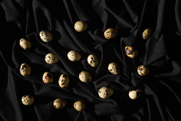 Αυγά ορτυκιού σε ένα κομμάτι μαύρο ύφασμα. Κοντινό πλάνο.. - Φωτογραφία, εικόνα