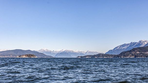 A view looking north up the Howe Sound towards Squamish, with snow-capped mountains and a windy morning on the Georgia Straight, British-Columbia - Foto, afbeelding