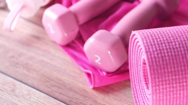  Kurzhantel in rosa, Gymnastikmatte und Wasserflasche auf Holzgrund  - Filmmaterial, Video