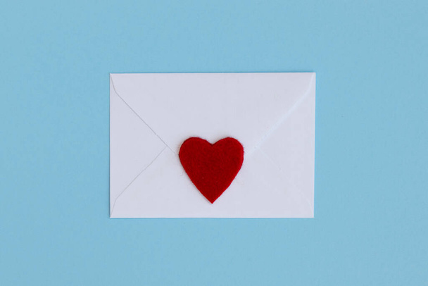 青い背景の上面に赤いハートの白い閉じた封筒。母の日。バレンタインデー。愛のシンボル. - 写真・画像