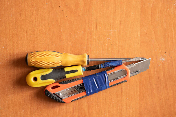 Kırtasiye bıçağı tornavida ve pense tahta bir arka planda yatıyor, tamir aletleri - Fotoğraf, Görsel