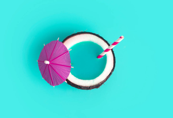 Tropické léto a dovolená minimální koncept. Kokosový ořech na modrém pozadí s koktejlovou slámou. Dovolená, cestování, plážový nápad. - Fotografie, Obrázek