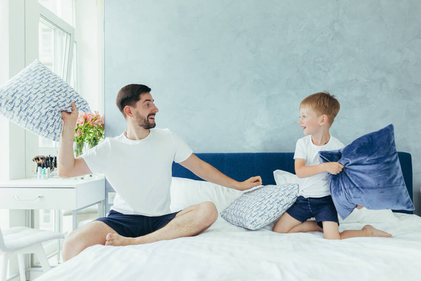 husband father playing with his children, two little boys brothers, in a large bedroom - Foto, Bild