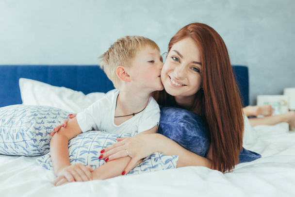 Young family woman, husband and son having fun together in a large bedroom in the morning - 写真・画像