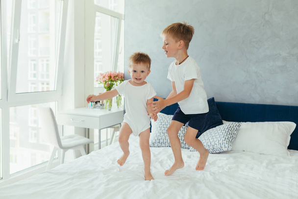 Two little boys brothers are playing in their parents' bedroom - Foto, afbeelding