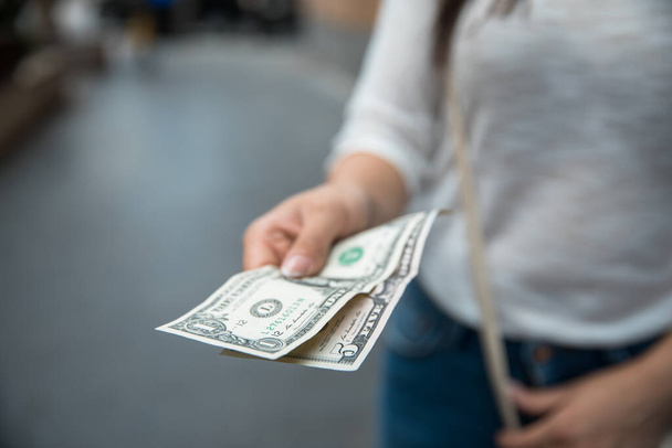 woman hand dollar in the street backgroun - Foto, Imagen