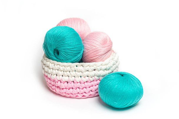 Pink and blue skeins of wool yarn on a white insulated background. Knitted basket with yarn - Photo, image