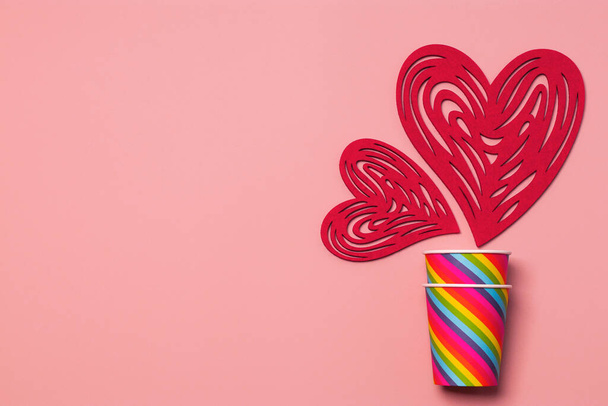 Día de San Valentín. Copas de papel arco iris, corazones sobre un fondo rosa suave. El concepto de orgullo gay, comunidad LGBT, adopción y derechos humanos. Libertad de elección. Copiar espacio - Foto, imagen
