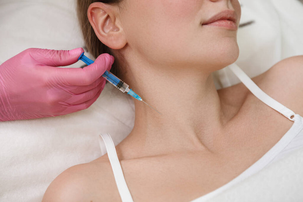 Cropped shot of a professional beautician giving filler injections into neck of female client - Foto, Imagem