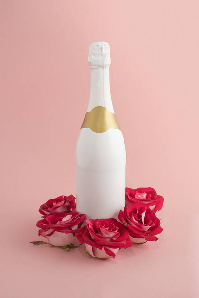 Pembe arka planda güller olan bir şişe şampanya. Asgari aşk konsepti. Anneler Günü ya da Sevgililer Günü fikri. - Fotoğraf, Görsel