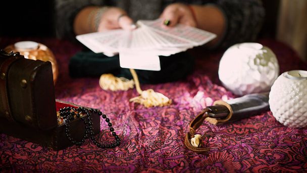 Fortune mains de caissier tenant des cartes de tarot sur la table près de bougies allumées - Photo, image