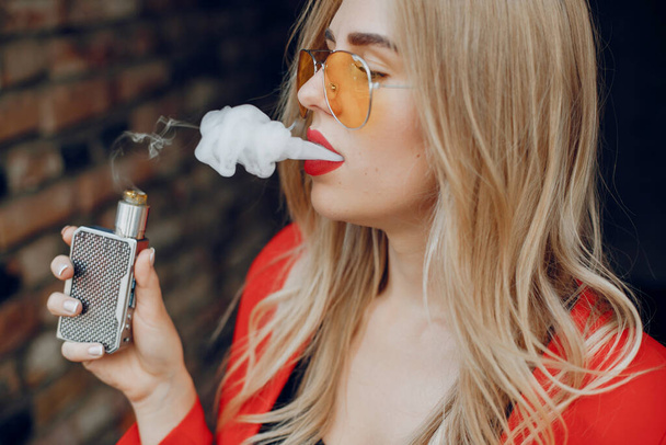 Stylish young girl in a city with vape - Foto, afbeelding