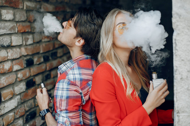 Stylish young couple with vape in a city - Fotó, kép