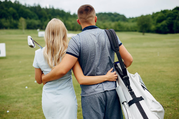 Beautiful couple playing golf on a golf course - Фото, зображення