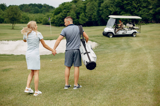 Beautiful couple playing golf on a golf course - Fotó, kép