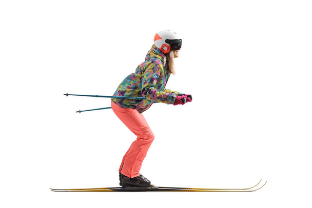 Full length profile shot of a female with a helmet skiing isolated on a white background - Photo, Image