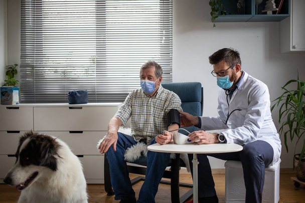 лікар консультування літнього чоловіка-пацієнта вдома собака на передньому плані
 - Фото, зображення