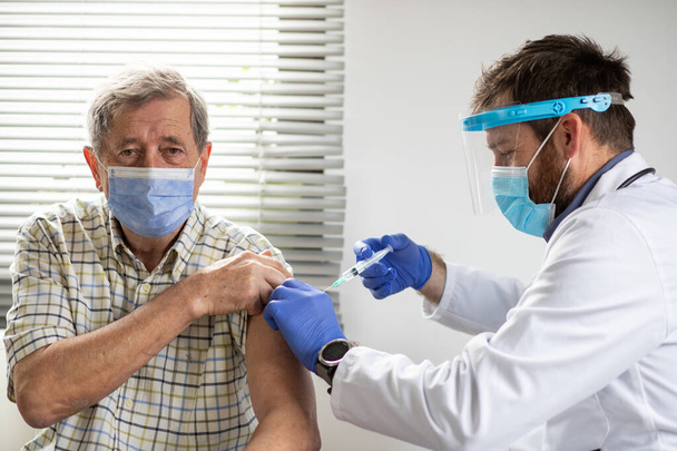 oudere man die een coronavirusvaccin krijgt - Foto, afbeelding