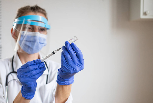 жінка-лікар готується давати вакцину проти коронавірусу
 - Фото, зображення