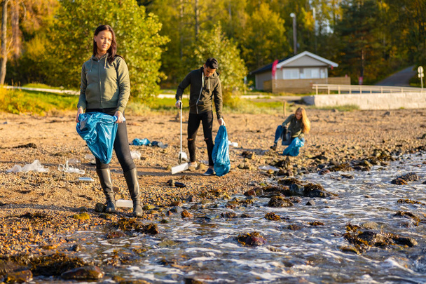 Umweltschutzteam sammelt Müll in Tüte am Strand auf - Foto, Bild