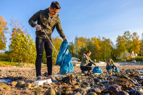 Összpontosított férfi takarítás strand csoport önkéntesek a napsütéses napon - Fotó, kép