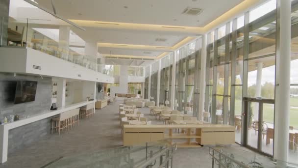 Panning δεν άτομα πυροβόλησε της σύγχρονης πολυτελές εστιατόριο εσωτερικό σε μπεζ χρώματα με πανοραμική παράθυρα που βρίσκονται στον πρώτο όροφο του γκολφ θέρετρο - Πλάνα, βίντεο