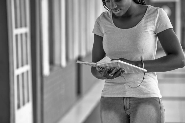 Afrikkalainen tyttö seisoo koulussa kirjallisesti hänen päiväkirjaansa. - Valokuva, kuva