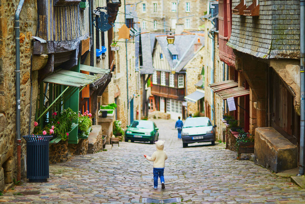 Urocza dziewczynka na ulicy Jerzual, jednej z najpiękniejszych ulic w średniowiecznym mieście Dinan, Bretania, Francja. Podróżowanie z dziećmi - Zdjęcie, obraz