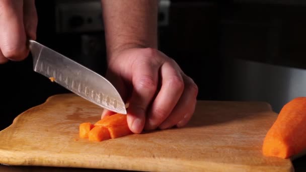 rebanando zanahorias. un hombre corta zanahorias en cubos con un cuchillo. - Imágenes, Vídeo