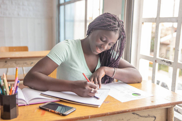 Szczęśliwa afrykańska dziewczyna w szkole podczas egzaminu. - Zdjęcie, obraz