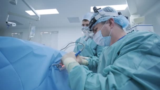 Operation of removing tonsils under deep anesthesia, surgeon uses latest devices, cold plasma method, cuts swelling in throat, doctor works with new probe, medical headlamp, surgical loupes - Footage, Video
