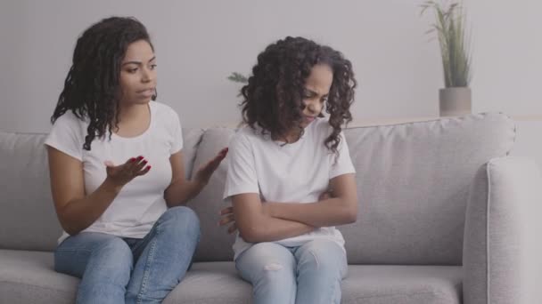Preocupada madre afroamericana regañando a hija adolescente por algo, ofendida chica sentada de nuevo a mamá - Imágenes, Vídeo