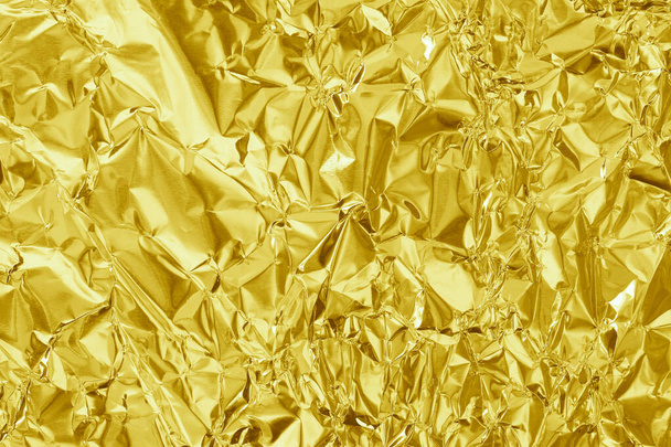 Fényes arany fólia textúra háttér, minta sárga csomagolópapír gyűrött és hullámos. - Fotó, kép