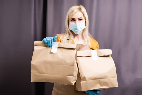 Caucasian young pretty woman, delivery worker medical mask. Female beautiful courier - 写真・画像