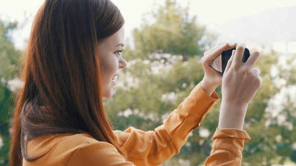 mujer al aire libre con un teléfono en sus manos tomando fotos de la naturaleza panorama descanso - Foto, Imagen
