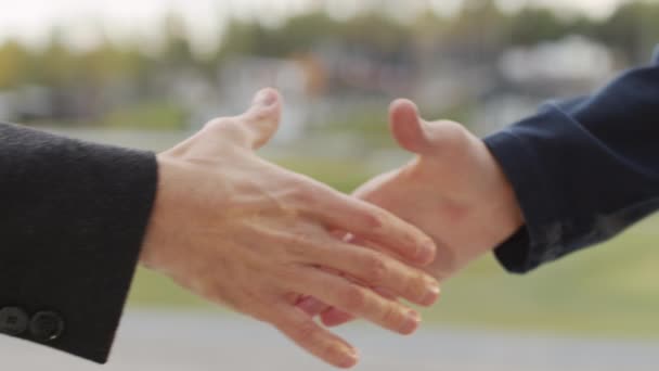 Langzaam sluiten van onherkenbare zakenmannen schudden handen buiten - Video