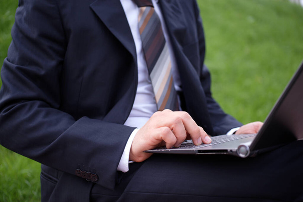 Homme d'affaires travaille avec son ordinateur portable dehors dans le parc - Photo, image