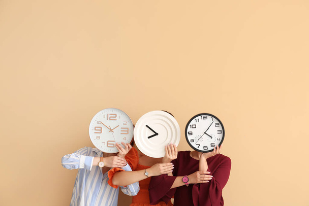 Women with clocks and wrist watches on color background - Photo, Image